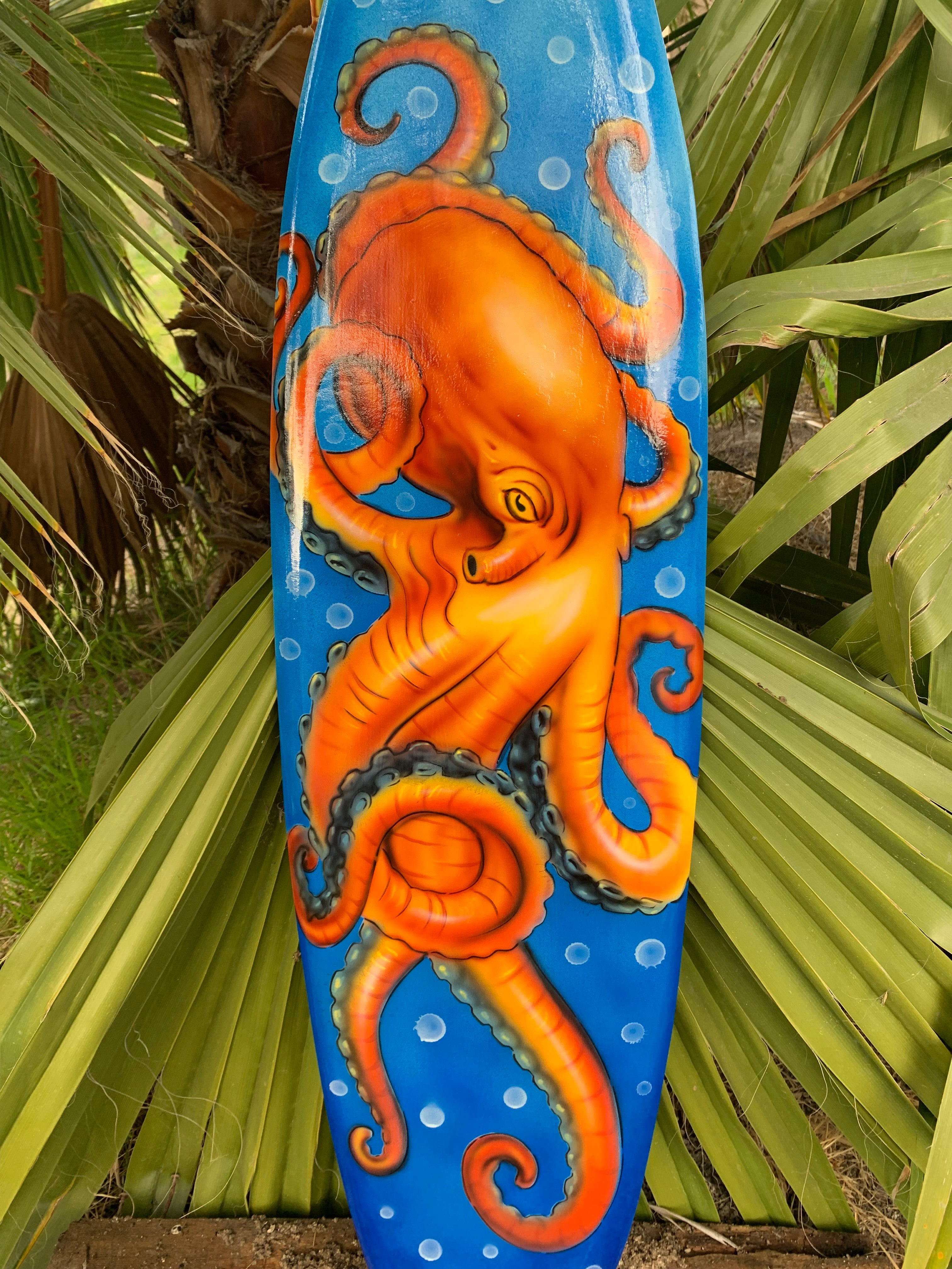 Orange octopus painting on a blue surfboard with bubbles